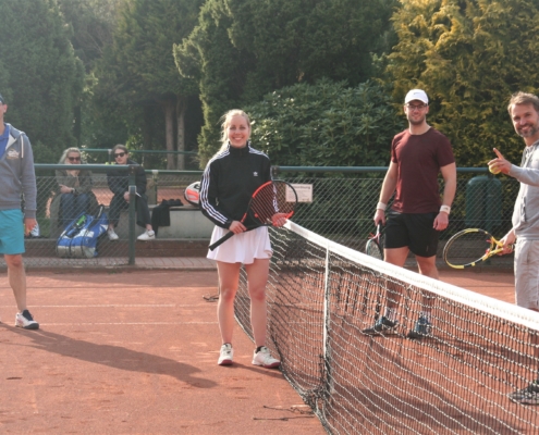 Vier Personen mit Tennisschläger gucken in die Kamera